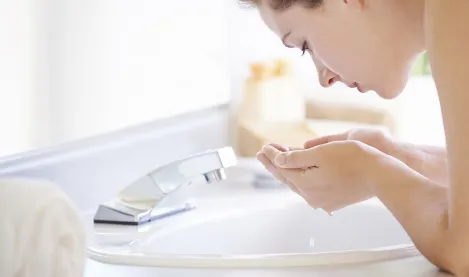 Mujer lavando su cara con agua 